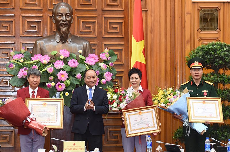 Thay mặt Đảng, Nhà nước, Thủ tướng Nguyễn Xuân Phúc trao Huân chương Lao động hạng Nhất cho VĐV Hoàng Xuân Vinh; trao Huân chương Lao động hạng Nhì cho HLV trưởng đội tuyển bắn súng Việt Nam Nguyễn Thị Nhung và trao Huân chương Hữu nghị cho ông Park Chung Gun, chuyên gia bắn súng Hàn Quốc. Ảnh: VGP/Quang Hiếu