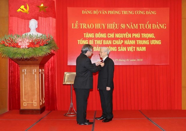 Ủy viên Bộ Chính trị, Thành viên Thường trực Ban Bí thư, Chủ nhiệm Ủy ban Kiểm tra Trung ương Trần Quốc Vượng gắn Huy hiệu 50 năm tuổi Đảng cho Tổng Bí thư Ban Chấp hành Trung ương Đảng Cộng sản Việt Nam Nguyễn Phú Trọng. (Ảnh: Trí Dũng/TTXVN)