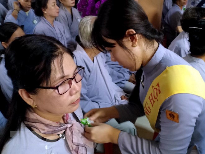 Các Phật tử thực hành Nghi thức 'Bông hồng cài áo' tại buổi lễ Vu Lan báo hiếu ở Cà Mau. (Ảnh: Kim Há/TTXVN)