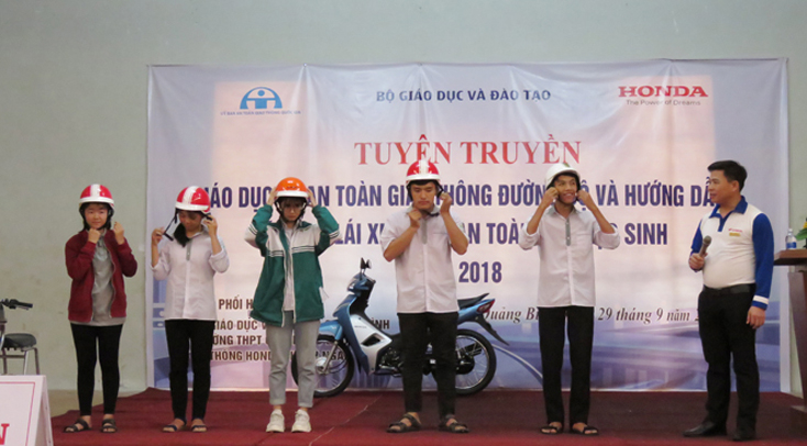 Các kỹ thuật viên hướng dẫn trực tiếp cho HS cách đội mũ bảo hiểm an toàn khi tham gia giao thông.