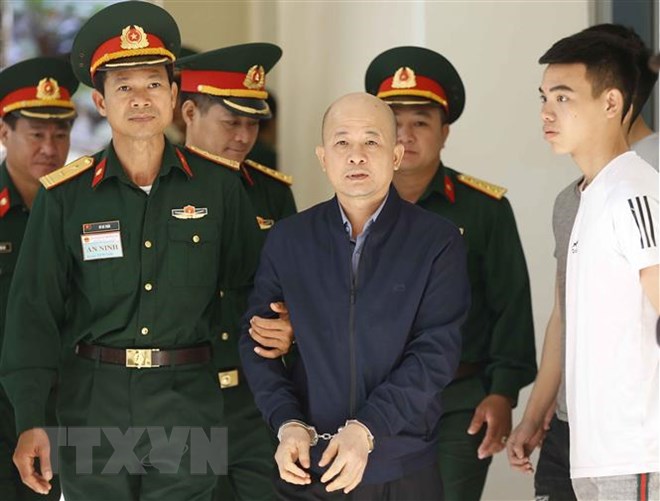 Lực lượng chức năng dẫn giải bị cáo Đinh Ngọc Hệ vào phiên xét xử. (Ảnh: Doãn Tấn/TTXVN)