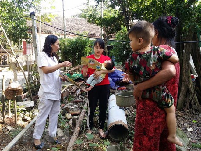Cán bộ y tế hướng dẫn người dân vệ sinh cá nhân phòng chống dịch bệnh. (Ảnh: TTXVN)