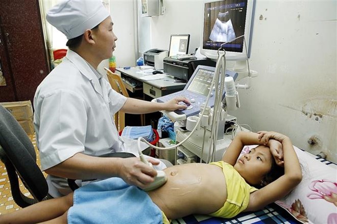 Bác sỹ khám cho bệnh nhân nhi có bảo hiểm y tế. (Ảnh: Dương Ngọc/TTXVN)