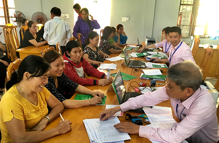 Cán bộ, nhân viên PGD NHCSXH huyện Bố Trạch giao dịch với bà con tại Điểm giao dịch xã Cự Nẫm.