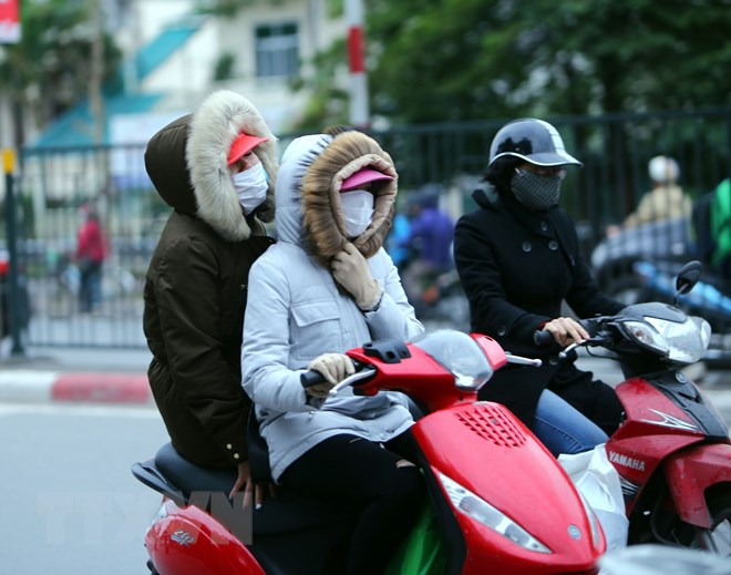 Người dân Hà Nội trang bị áo ấm chống rét, trên đường Giải Phóng (Hà Nội). (Ảnh: Danh Lam/TTXVN)