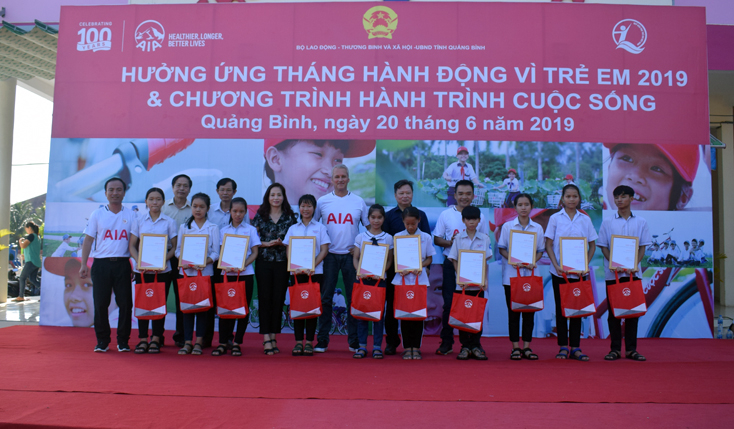Các đại biểu trao quà và hợp đồng bảo hiểm cho các học sinh nghèo vượt khó ở TP. Đồng Hới