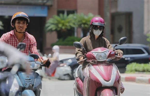 Người dân ra đường với trang phục kín mít để tránh cái nắng gay gắt. (Ảnh: Thành Đạt/TTXVN)