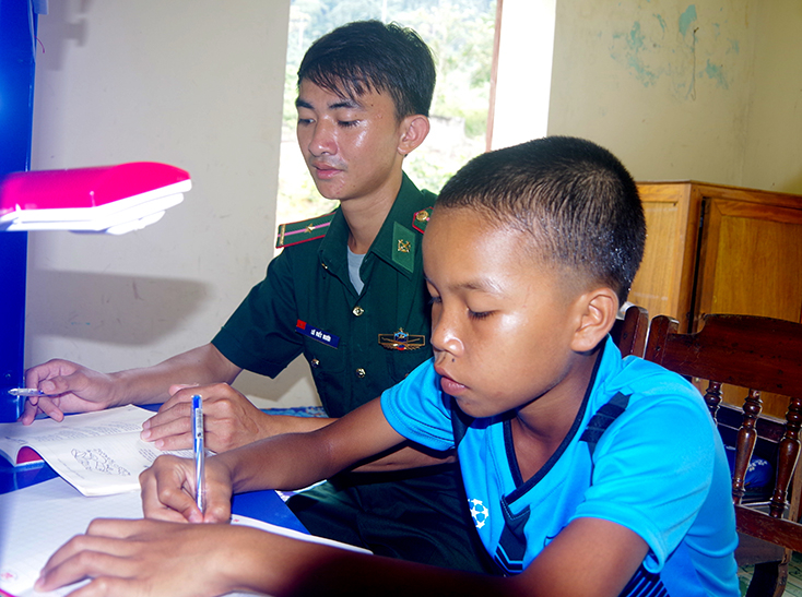Cán bộ, chiến sỹ Đồn Biên phòng Cà Xèng hướng dẫn em Cao Ngọc Huyên học bài.
