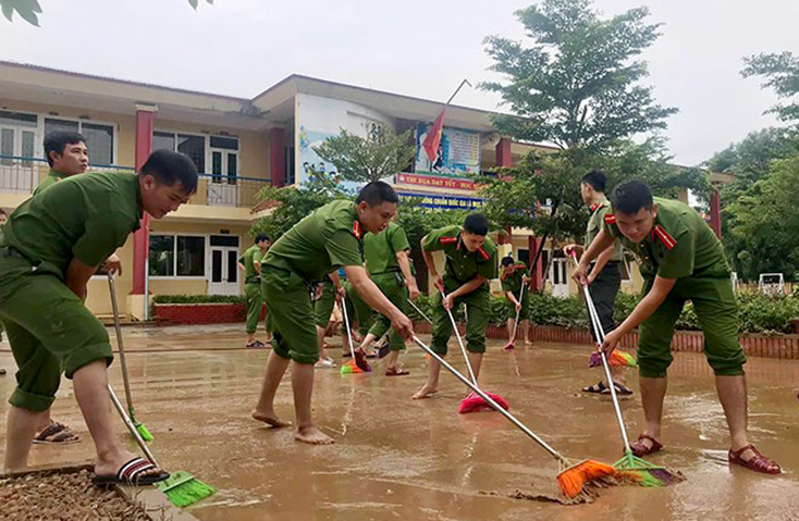 Lực lượng Công an tham gia hỗ trợ người dân vệ sinh môi trường sau lũ.