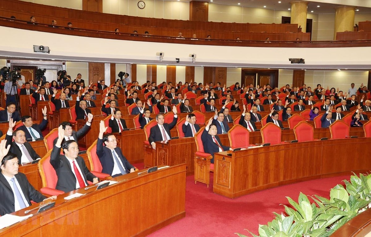 Các đồng chí lãnh đạo Đảng, Nhà nước và các đại biểu biểu quyết thông qua Nghị quyết Hội nghị Trung ương lần thứ mười một. (Ảnh: Trí Dũng/TTXVN)