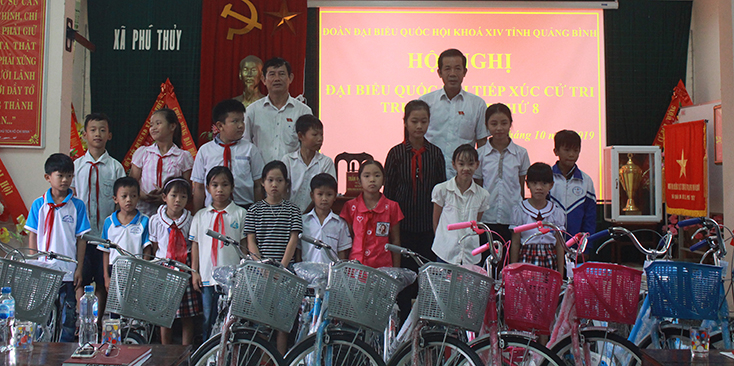 Các ĐBQH trao xe đạp cho các em học sinh ở xã Phú Thủy. 