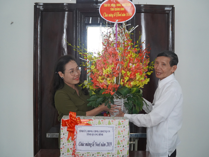 Đồng chí Phạm Thị Hân, Ủy viên Ban Thường vụ Tỉnh ủy, Chủ tịch Ủy ban MTTQVN tỉnh tặng hoa chúc mừng Giáng sinh cho linh mục Hồ Thái Bạch tại Giáo họ Đồng Đưng, xã Quảng Minh, TX. Ba Đồn.