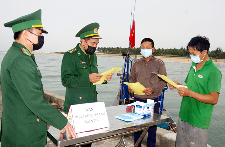 Cán bộ Trạm kiểm soát, Đồn BP Nhật Lệ tuyên truyền, phát khẩu trang phòng, chống dịch Covid-19 cho ngư dân.