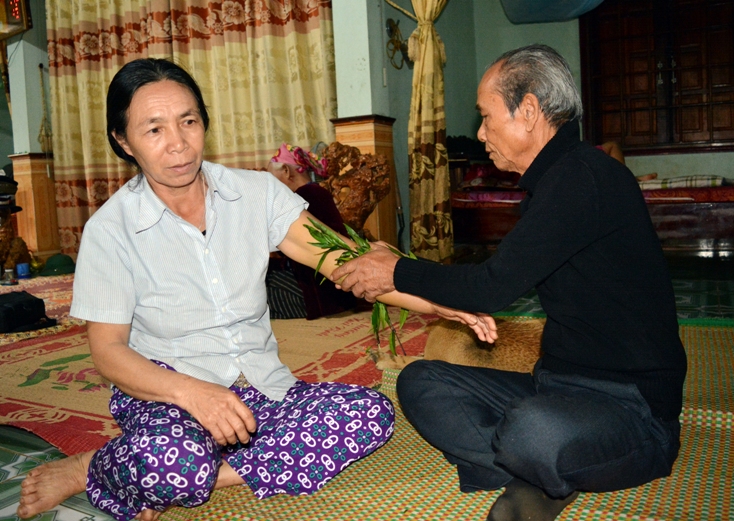    Bà Trần Thị Nga, ở thôn Bắc Kim Sen bị chớm gãy tay đang được già Thu thăm khám, áp lá thuốc.