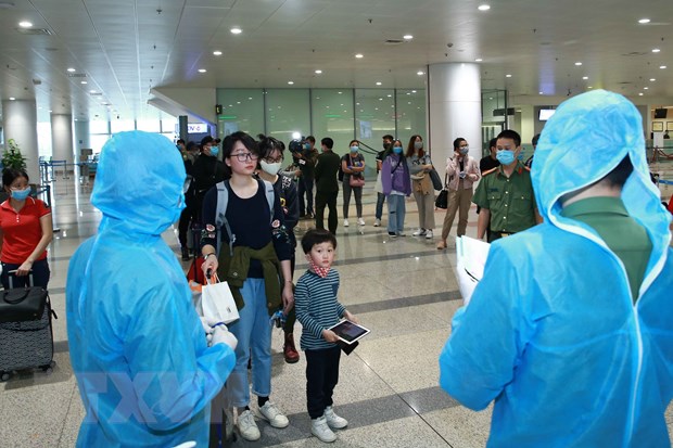 Lực lượng Công an cửa khẩu Cảng hàng không Quốc tế Nội Bài kiểm tra hộ chiếu, hướng dẫn và phát thẻ cho hành khách đi cách ly. (Ảnh: Doãn Tấn/TTXVN)