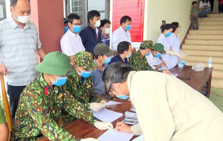 Thiếu tá Nguyễn Thành Long (ngồi thứ hai từ trái qua) cùng đồng đội hướng dẫn công dân làm thủ tục hoàn thành cách ly tập trung.