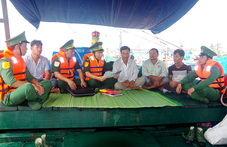 Cán bộ trạm kiểm soát, Đồn Biên phòng CK Cảng Gianh, BĐBP Quảng Bình phát tờ rơi, tuyên truyền pháp luật và tặng cờ Tổ quốc cho ngư dân trên biển (ảnh: Châu Thành) 