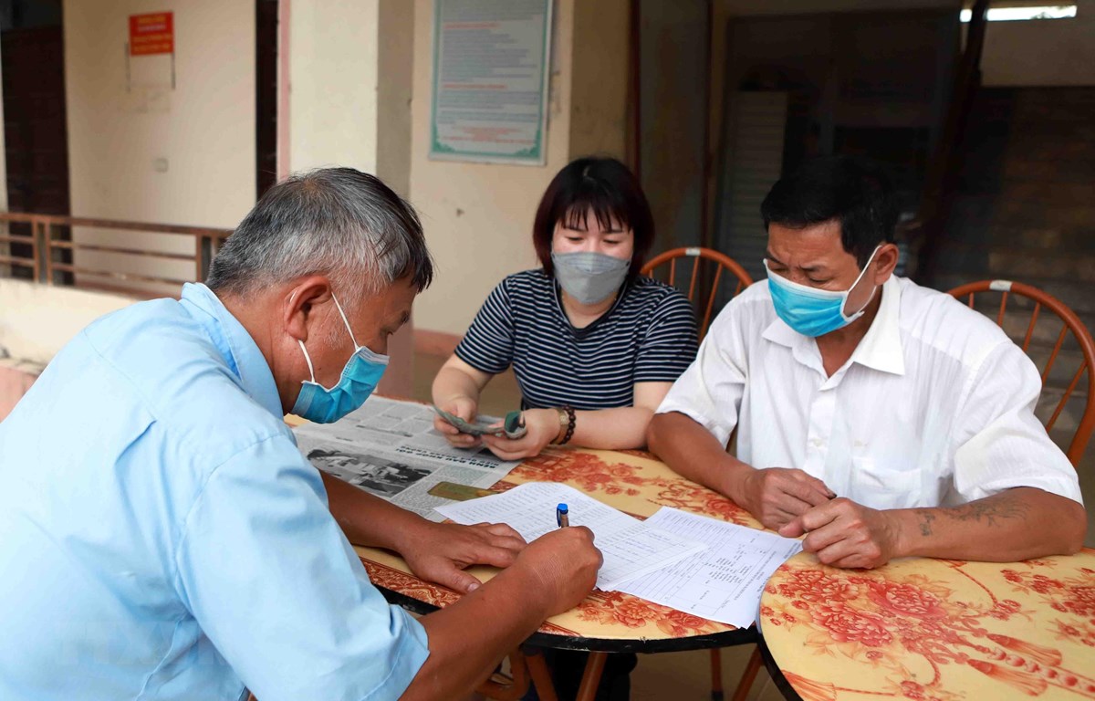  Chi trả tiền hỗ trợ cho người dân gặp khó khăn do COVID-19. (Ảnh: Hoàng Hùng/TTXVN)