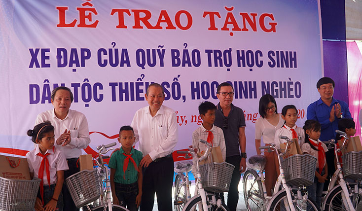 Đồng chí Phó Thủ tướng Thường trực Chính phủ Trương Hòa Bình và đồng chí Bí thư Tỉnh ủy Hoàng Đăng Quang, Bí thư thứ nhất Trung ương đoàn Lê Quốc Phong  trao quà cho học sinh có hoàn cảnh khó khăn tại