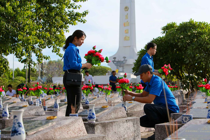 Các đoàn viên thanh niên thay hoa tại các phần mộ liệt sỹ.