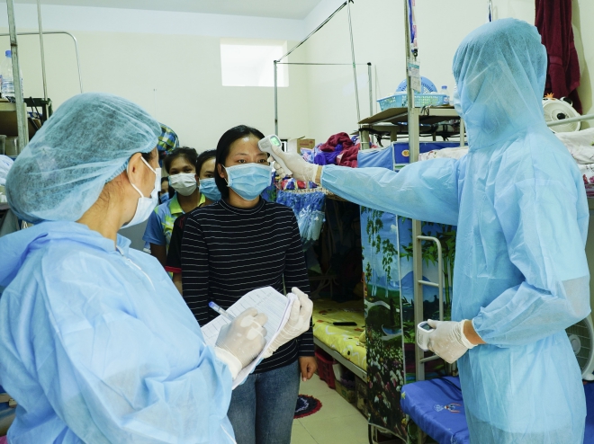  Nhân viên y tế đo thân nhiệt và kiểm tra sức khỏe cho người dân. Ảnh: Xuân Tư – TTXVN