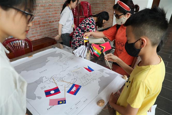 Các em nhỏ tham gia hoạt động trải nghiệm: tìm hiểu cờ, tiền tệ và thủ đô các nước. Ảnh: Thành Đạt - TTXVN