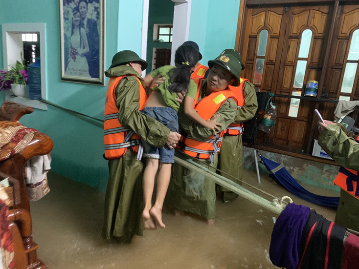 Chỉ huy Công an TX. Ba Đồn đưa người dân vùng bị ngập sâu đến nơi an toàn khi lũ dữ đang diễn ra.