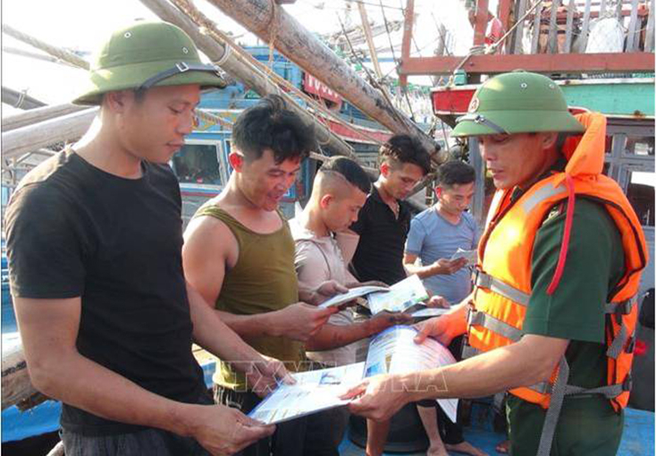 Phát tờ rơi tuyên truyền ngư dân khai thác hải sản đúng các quy định.