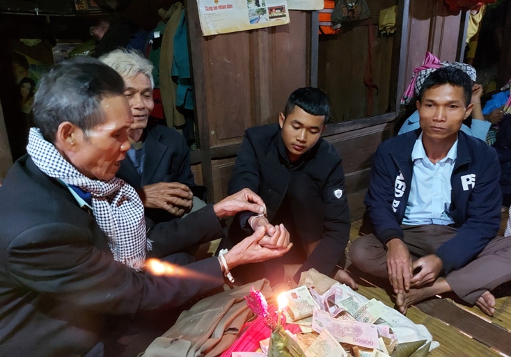 Anh Hồ Diên(thứ 2 bên phải) ở bản Lé (xã Trọng Hóa) được già làng buộc chỉ cổ tay trước khi lên đường nhập ngũ. 