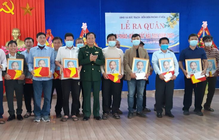 Đại tá Đinh Xuân Hùng tặng cờ Tổ quốc và ảnh Bác Hồ cho bà con ngư dân xã Đức Trạch.
