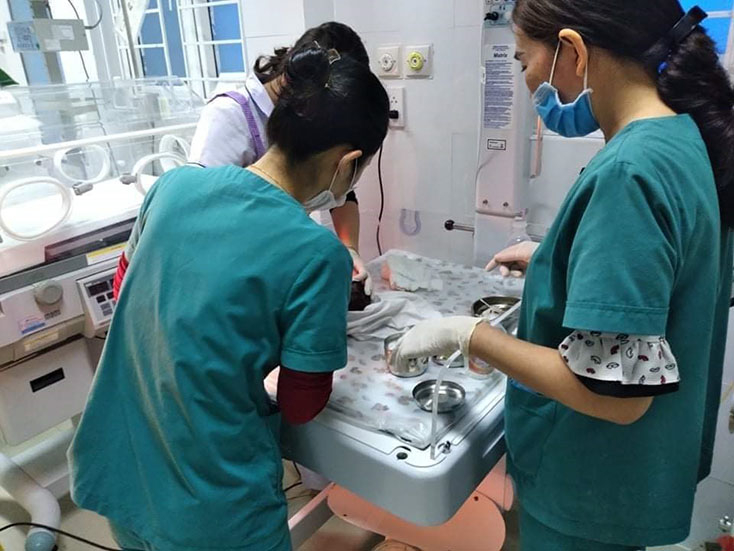 Cán bộ y tế đang chăm sóc, vệ sinh cho cháu bé