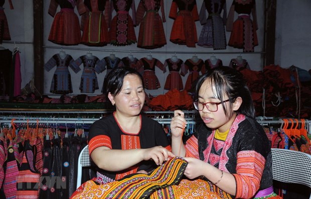  Chị Tráng Thị Dua (bên trái) truyền dạy nghề thêu, may truyền thống của đồng bào dân tộc Mông cho con gái. (Ảnh: Quang Quyết/TTXVN)