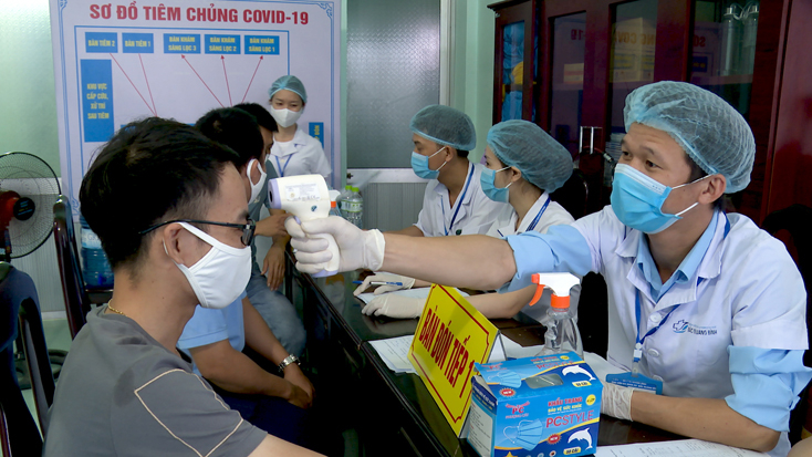 Đo thân nhiệt cho các đối tượng tiêm vắc-xin Covid-19.