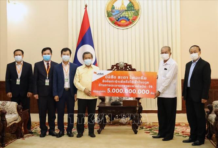 Phó Thủ tướng Lào Kikeo Khaykhamphithoune (phải), Trưởng Ban Chỉ đạo Quốc gia Lào về phòng chống COVID-19, tiếp nhận hỗ trợ của Công ty Unitel. Ảnh: Phạm Kiên/Pv TTXVN tại Lào.