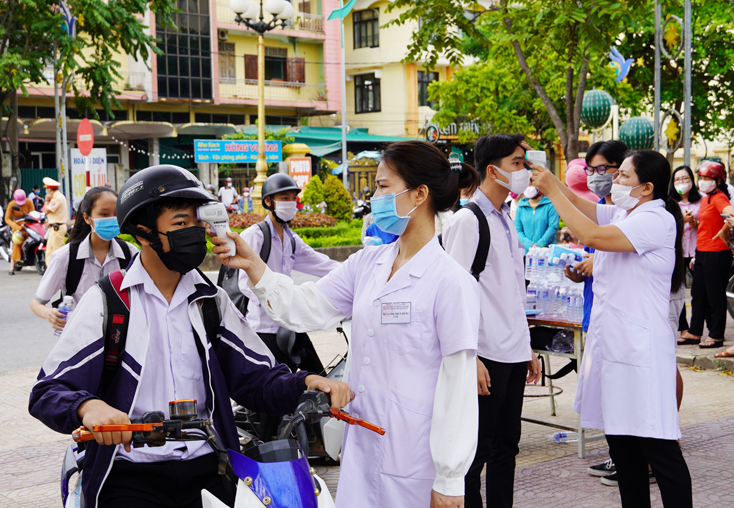 Cán bộ y tế đo thân nhiệt cho thí sinh trước khi vào trường thi.