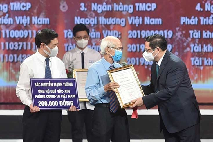 Thủ tướng Chính phủ Phạm Minh Chính trao chứng nhận, hoa cảm ơn bác Nguyễn Mạnh Tường 82 tuổi, cán bộ hưu trí ngành đường sắt. Ảnh: Viết Chung