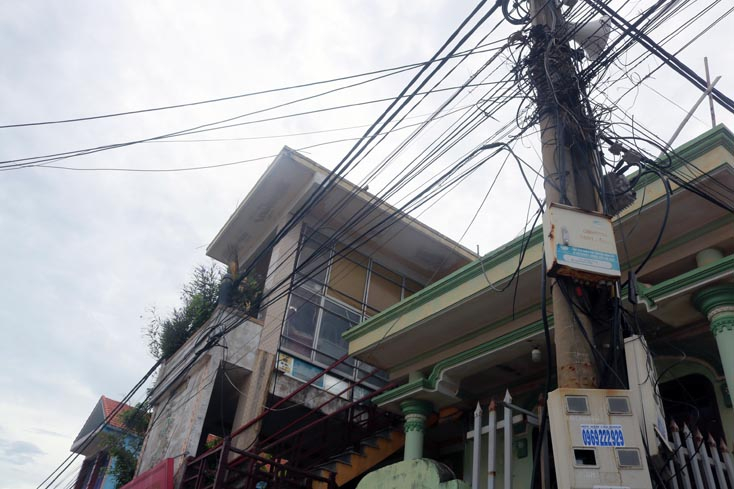 Hệ thống đường dây điện, cáp viễn thông kéo vắt qua phần mái hiên nhà ở của người dân xã Đức Trạch. 