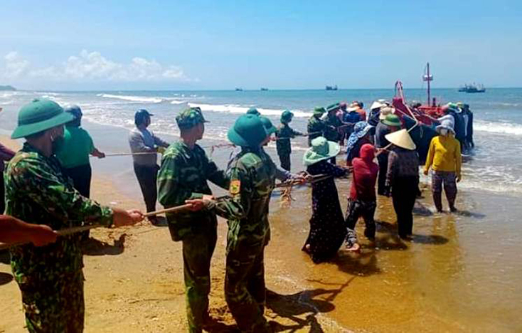 Cán bộ, chiến sĩ Đồn Biên phòng Lý Hòa cùng nhân dân địa phương kéo tàu bị nạn vào bờ.