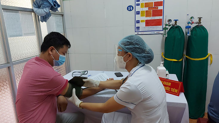 Cán bộ y tế thực hiện khám sàng lọc cho người dân trước khi tiêm chủng