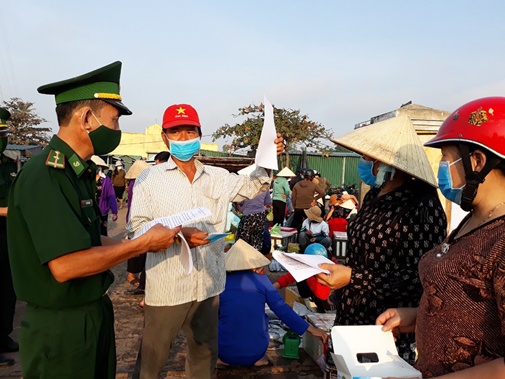 Cán bộ, chiến sỹ Đồn Biên phòng Lý Hòa phát tờ rơi và tuyên truyền phòng, chống dịch ở nơi tập trung đông người.
