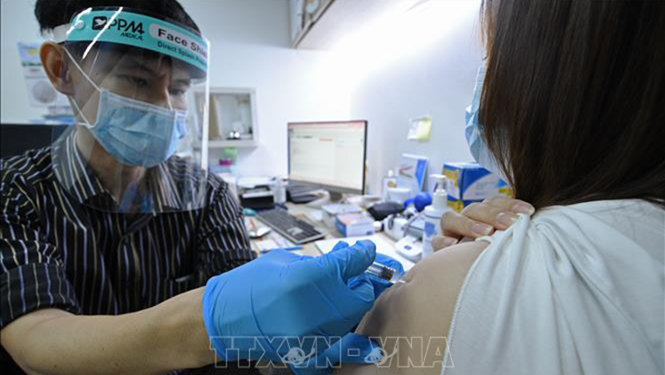 Nhân viên y tế tiêm vaccine phòng COVID-19 cho người dân tại Singapore. Ảnh: THX/TTXVN