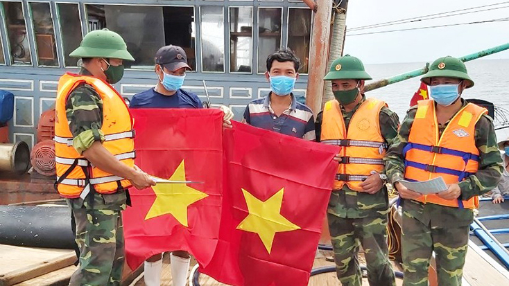 Cán bộ, chiến sĩ Hải đội 2, BĐBP tỉnh tặng cờ Tổ quốc và tuyên truyền ngư dân thực hiện các biện pháp phòng, chống dịch Covid-19.