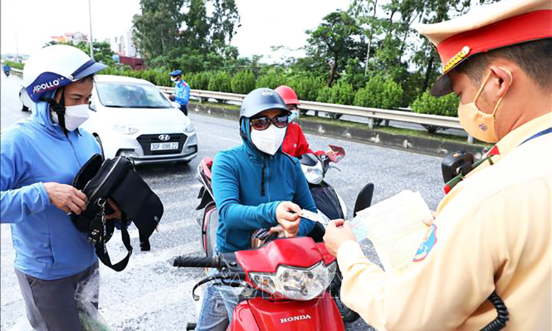 Kiểm tra người tham gia giao thông tại chốt kiểm soát dịch COVID-19 tại ngã 3 Cầu Giẽ, huyện Phú Xuyên hướng từ Hà Nam về Hà Nội trên tuyến Quốc lộ 1A. Ảnh: Phạm Kiên/TTXVN