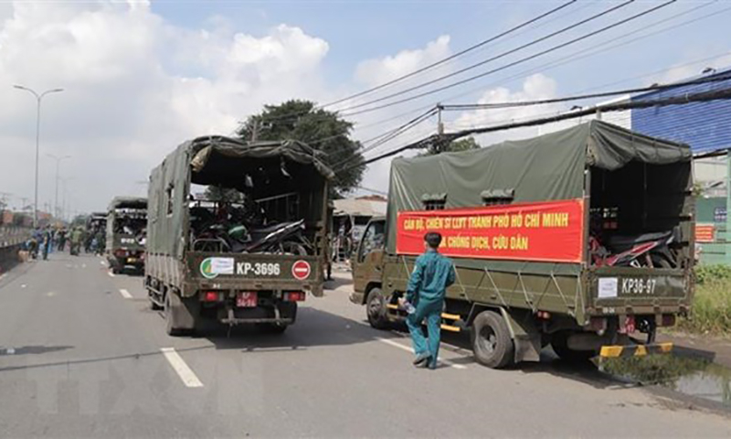 Lực lượng kiểm soát quân sự vận chuyển xe máy cho người dân lên xe ôtô chở về quê. (Ảnh: TTXVN phát)