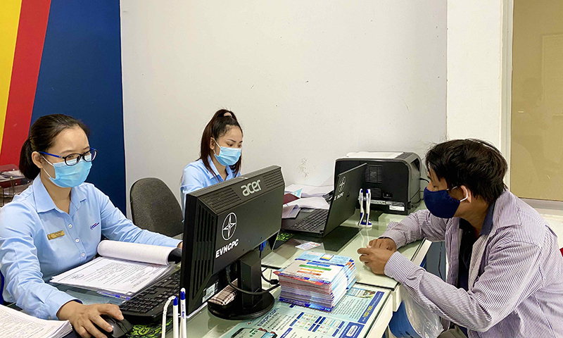 Cán bộ, công nhân PC Quảng Bình hỗ trợ khách hàng đăng ký tài khoản thanh toán tiền điện không dùng tiền mặt.