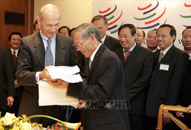  Trước sự chứng kiến của Phó Thủ tướng Phạm Gia Khiêm, Tổng Giám đốc WTO Pascal Lamy trao các văn kiện về việc kết nạp Việt Nam trở thành thành viên chính thức thứ 150 của WTO cho Bộ trưởng Thương mại Việt Nam Trương Đình Tuyển, tại buổi lễ kết nạp Việt Nam vào WTO, ngày 7-11-2006, tại trụ sở WTO ở Geneva (Thụy Sĩ). Ảnh tư liệu: AFP - TTXVN phát