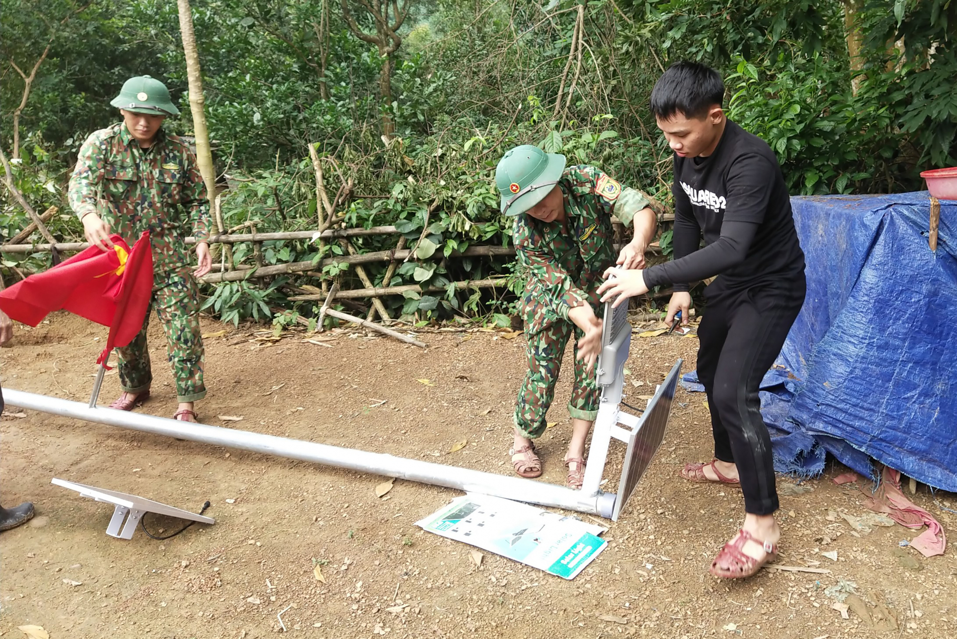 BĐBP và đoàn thiện nguyện thi công lắp đặt cột đèn.