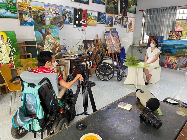  Anh Đinh Công Duy ngồi trên xe lăn đang thực hiện phóng sự về Nhà May Mắn. (Ảnh: VTV)