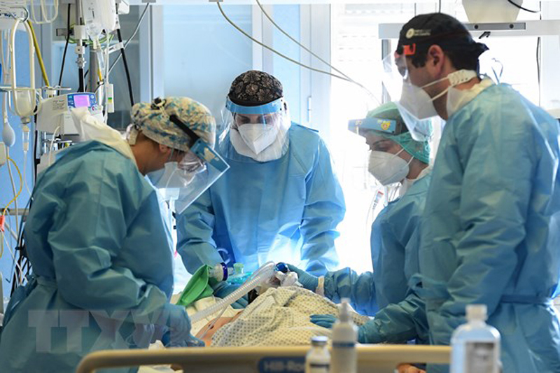 Nhân viên y tế điều trị cho bệnh nhân COVID-19. (Ảnh: AFP/TTXVN)