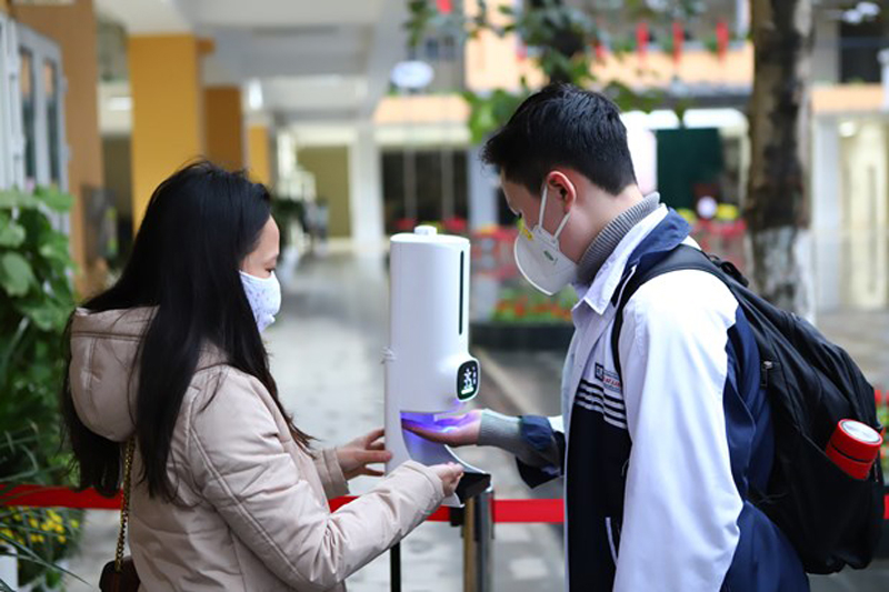 Học sinh thực hiện khử khuẩn trước khi vào lớp. (Ảnh: Nguyễn Nam/Vietnam+)